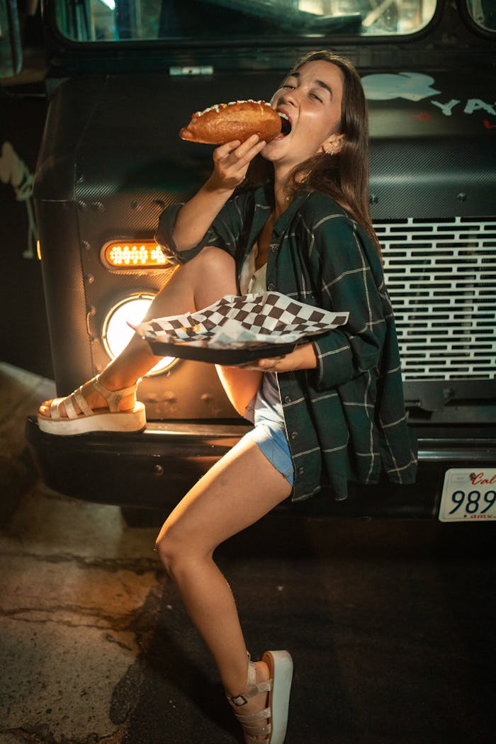 Mastering the First Impression: Your intriguing post title goes here A young woman joyfully eats a large sandwich at a food truck at night.