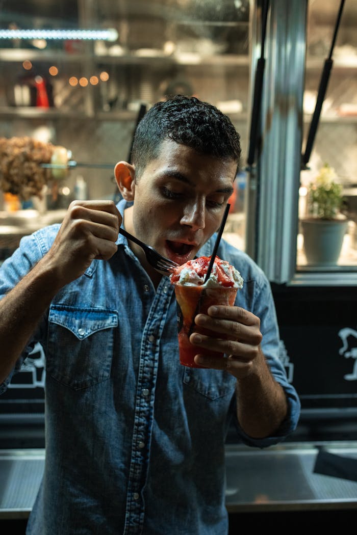 Crafting Captivating Headlines: Your awesome post title goes here A man enjoying a frozen dessert in front of a food truck at night, capturing a taste of street food culture.